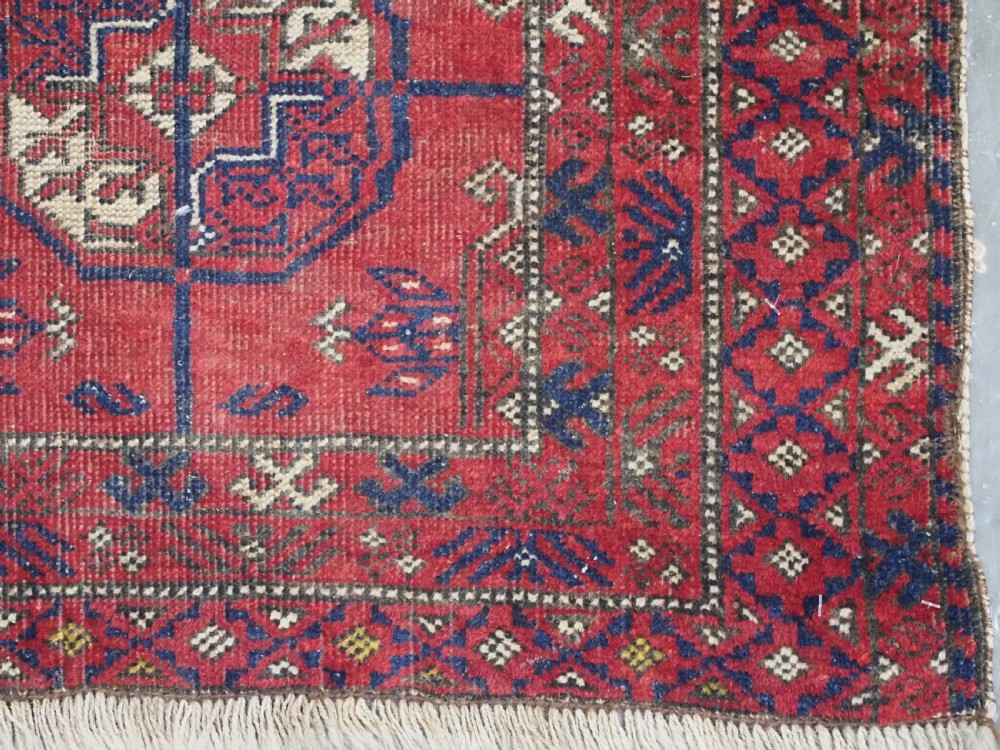 A hand-knotted antique Baluch prayer rug featuring a deep red ground, geometric octagonal medallions, an arched mihrab motif at the top, and multi-band patterned borders. View XII