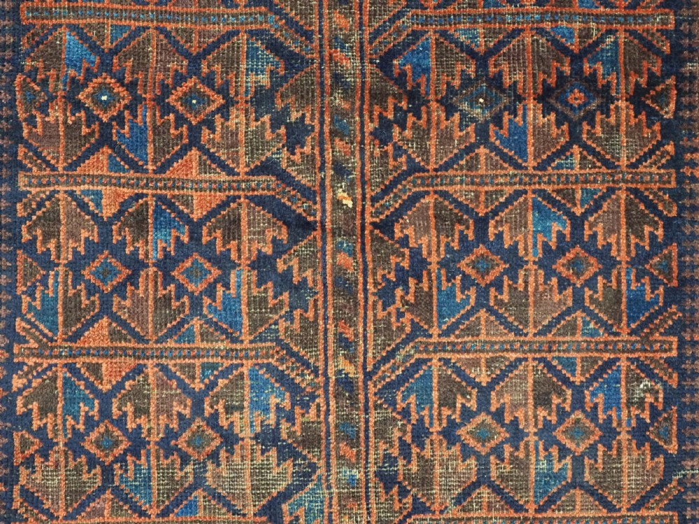 An antique hand-knotted Baluch prayer rug featuring a dark blue central field decorated with geometric motifs framed by a stepped arch and multi-tiered red borders. View X