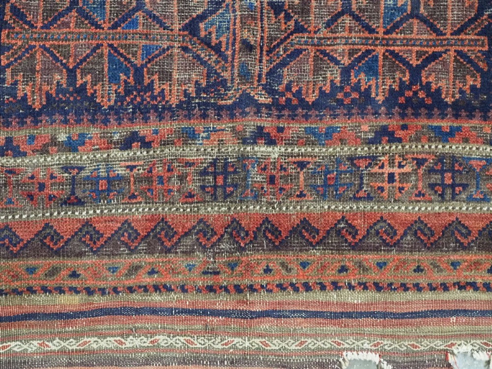 An antique hand-knotted Baluch prayer rug featuring a dark blue central field decorated with geometric motifs framed by a stepped arch and multi-tiered red borders. View XI