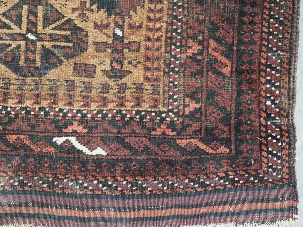 An antique woven Baluch prayer rug with a central tree of life design in camel brown and dark red tones. View X