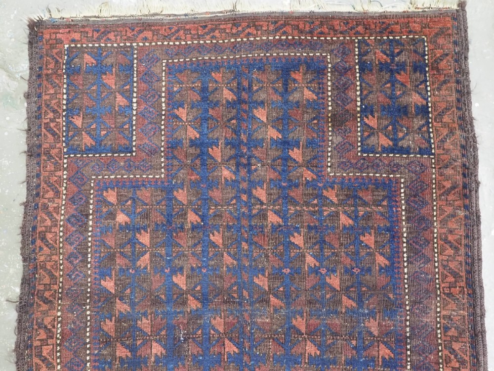 An antique Timuri Baluch wool prayer rug featuring a deep blue field woven with a repeating brown leaf motif and framed by geometric borders. View III