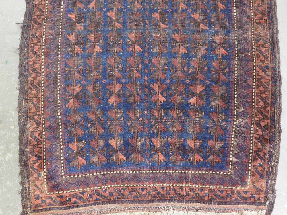 An antique Timuri Baluch wool prayer rug featuring a deep blue field woven with a repeating brown leaf motif and framed by geometric borders. View IV