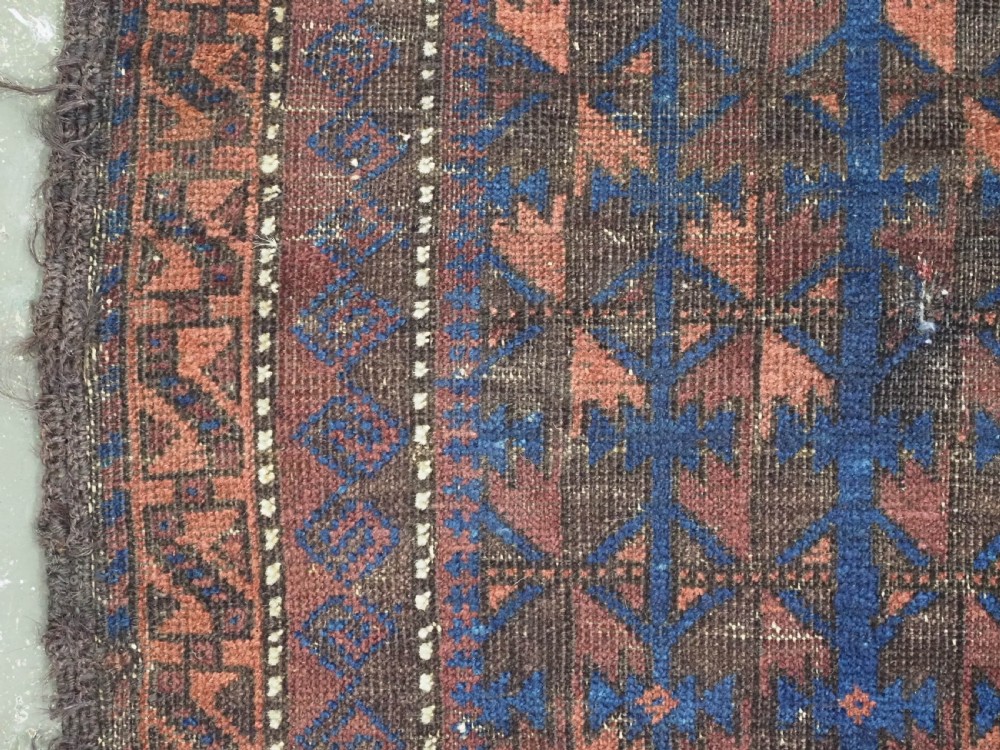 An antique Timuri Baluch wool prayer rug featuring a deep blue field woven with a repeating brown leaf motif and framed by geometric borders. View VI