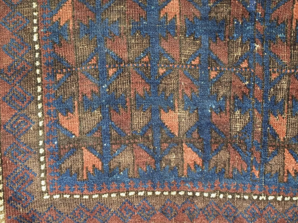 An antique Timuri Baluch wool prayer rug featuring a deep blue field woven with a repeating brown leaf motif and framed by geometric borders. View IX