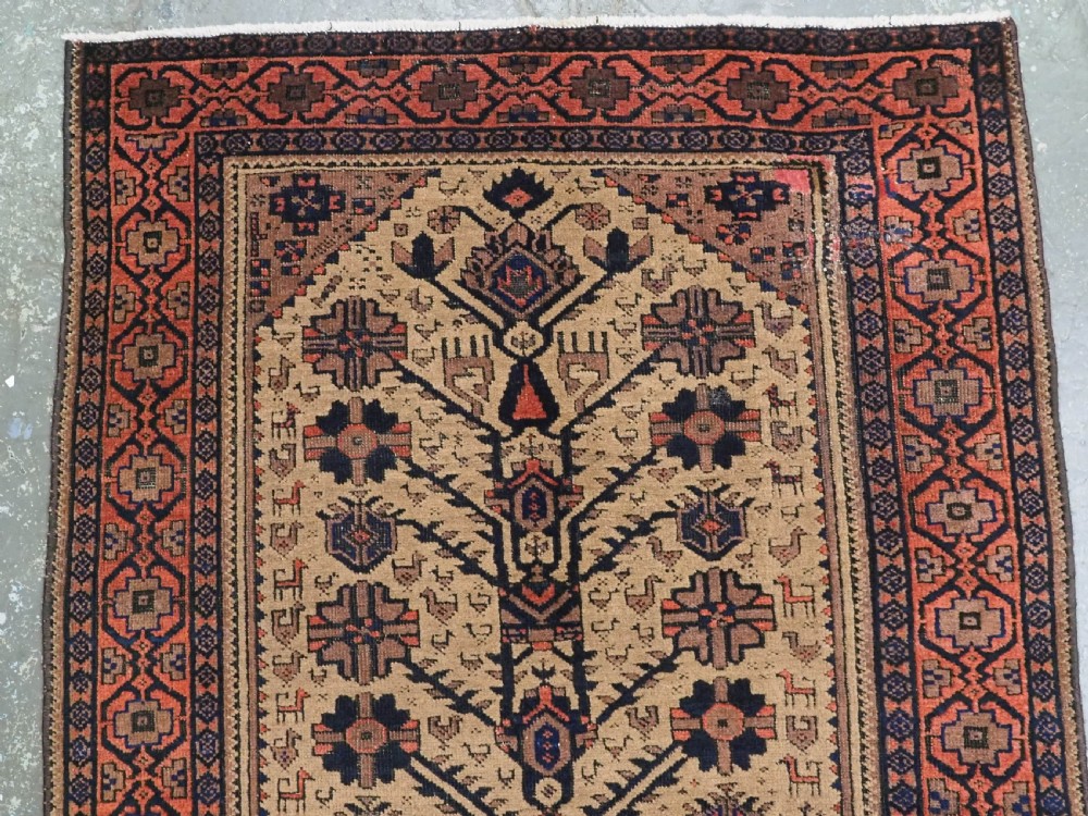 A rectangular late 19th-century Baluch tribal rug with a camel wool field, featuring a central stylised tree motif and terracotta geometric borders. View III