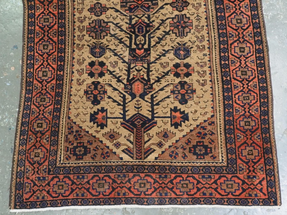 A rectangular late 19th-century Baluch tribal rug with a camel wool field, featuring a central stylised tree motif and terracotta geometric borders. View V