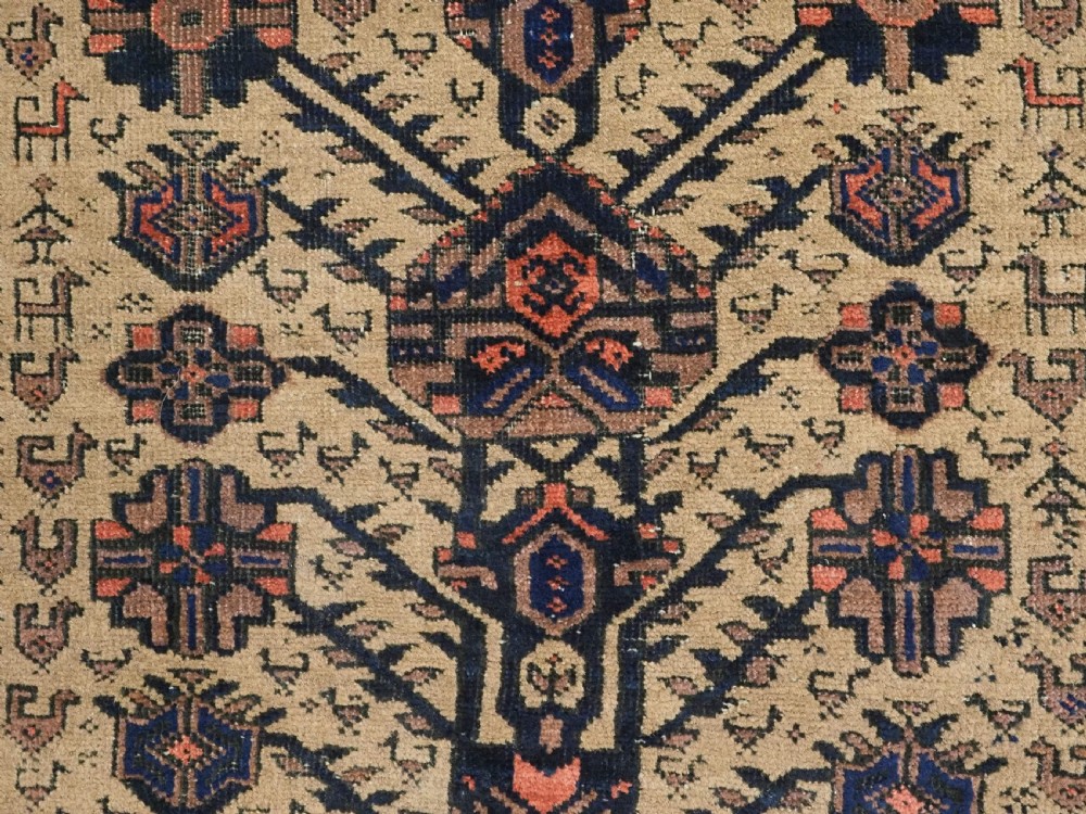 A rectangular late 19th-century Baluch tribal rug with a camel wool field, featuring a central stylised tree motif and terracotta geometric borders. View X