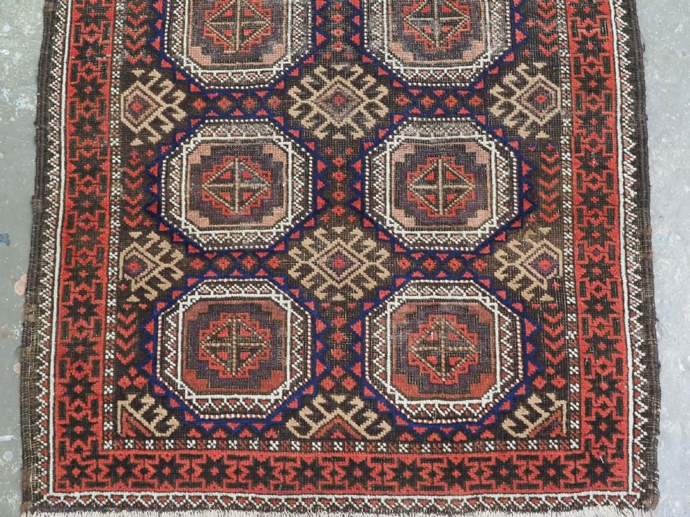 An antique hand-knotted Salar Khani Baluch wool rug featuring a central column of octagonal geometric medallions framed by intricate patterned borders in dark brown, deep red, and navy blue tones. View V