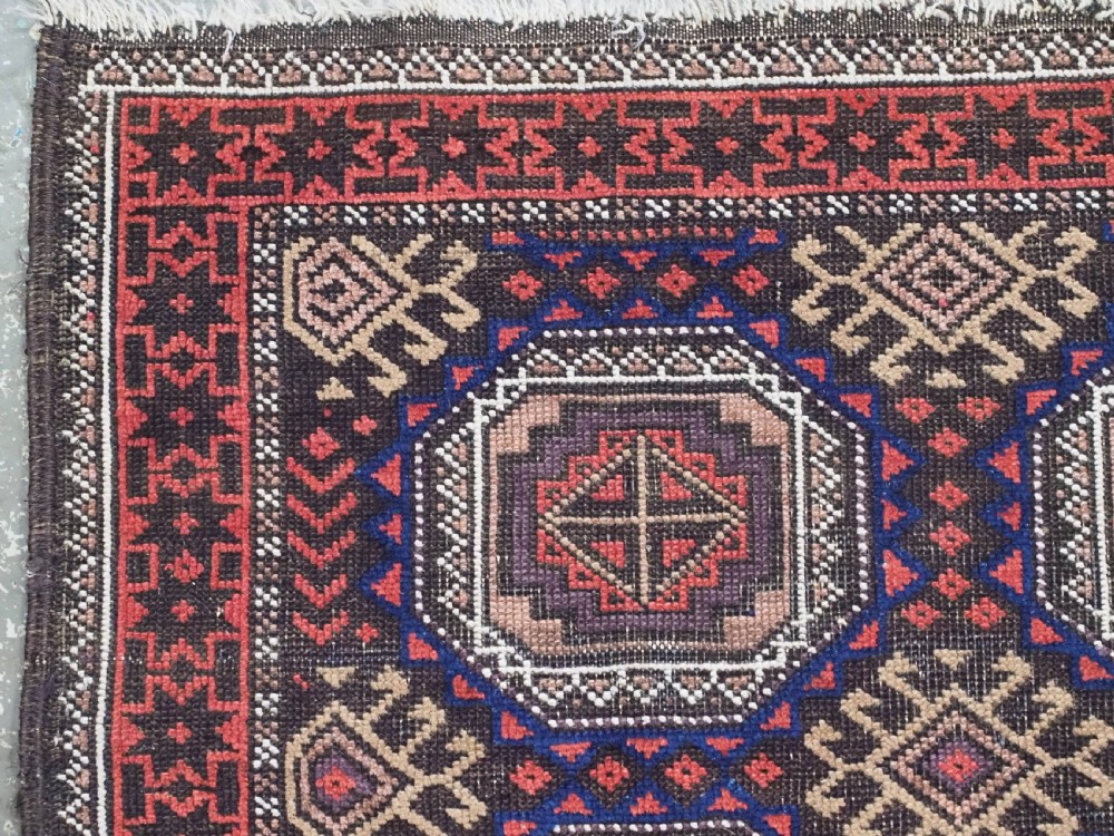 An antique hand-knotted Salar Khani Baluch wool rug featuring a central column of octagonal geometric medallions framed by intricate patterned borders in dark brown, deep red, and navy blue tones. View VI