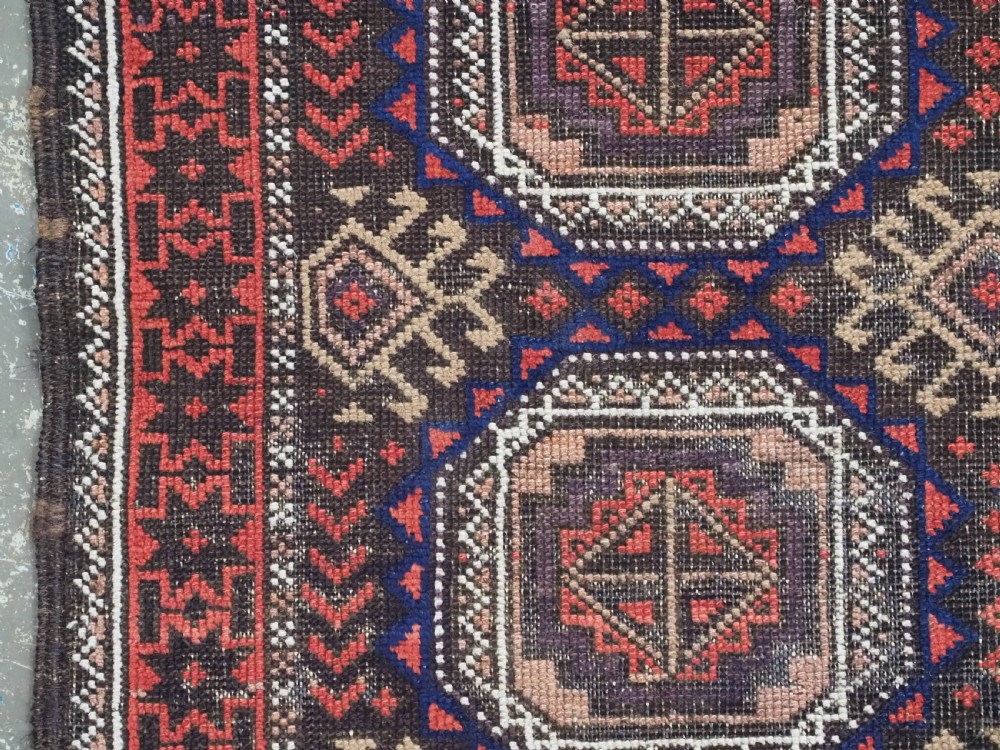 An antique hand-knotted Salar Khani Baluch wool rug featuring a central column of octagonal geometric medallions framed by intricate patterned borders in dark brown, deep red, and navy blue tones. View VII