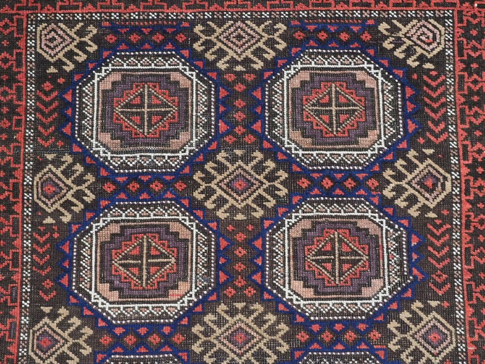 An antique hand-knotted Salar Khani Baluch wool rug featuring a central column of octagonal geometric medallions framed by intricate patterned borders in dark brown, deep red, and navy blue tones. View VIII
