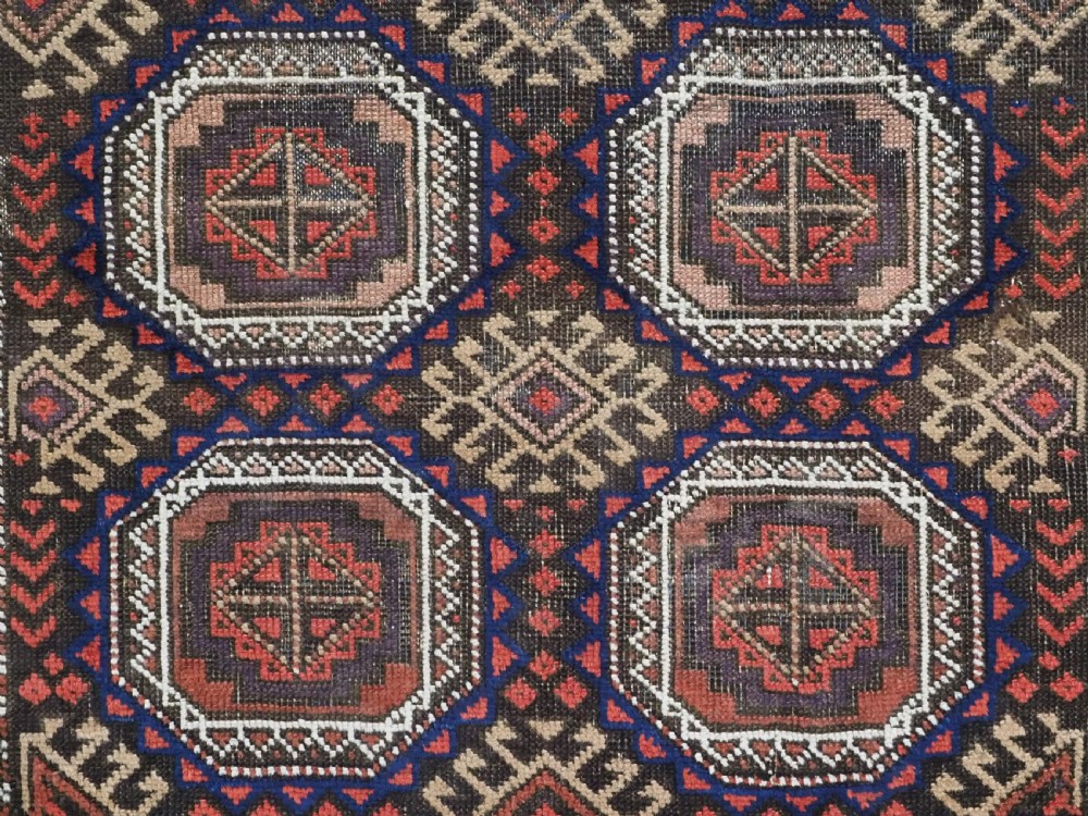 An antique hand-knotted Salar Khani Baluch wool rug featuring a central column of octagonal geometric medallions framed by intricate patterned borders in dark brown, deep red, and navy blue tones. View IX