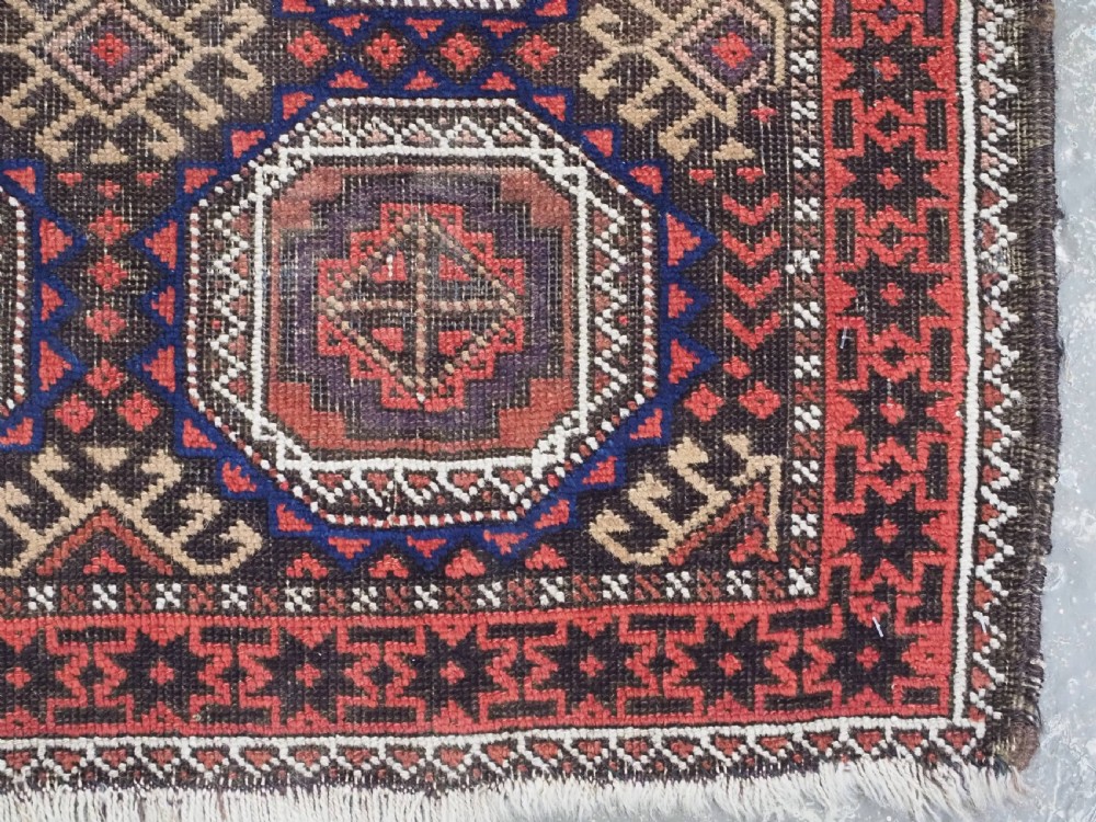 An antique hand-knotted Salar Khani Baluch wool rug featuring a central column of octagonal geometric medallions framed by intricate patterned borders in dark brown, deep red, and navy blue tones. View X