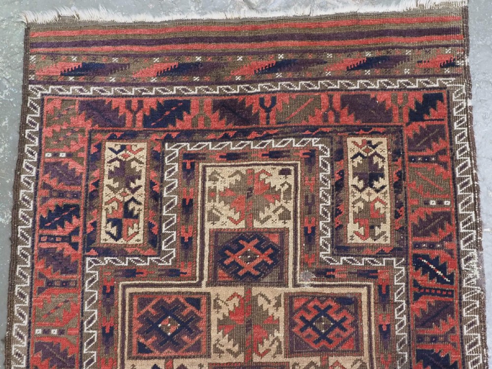 An antique hand-knotted wool prayer rug featuring a central mihrab pattern surrounded by geometric square motifs in dark brown, terracotta, and navy blue tones. View II