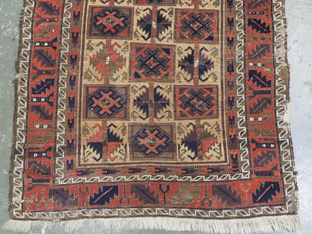 An antique hand-knotted wool prayer rug featuring a central mihrab pattern surrounded by geometric square motifs in dark brown, terracotta, and navy blue tones. View III