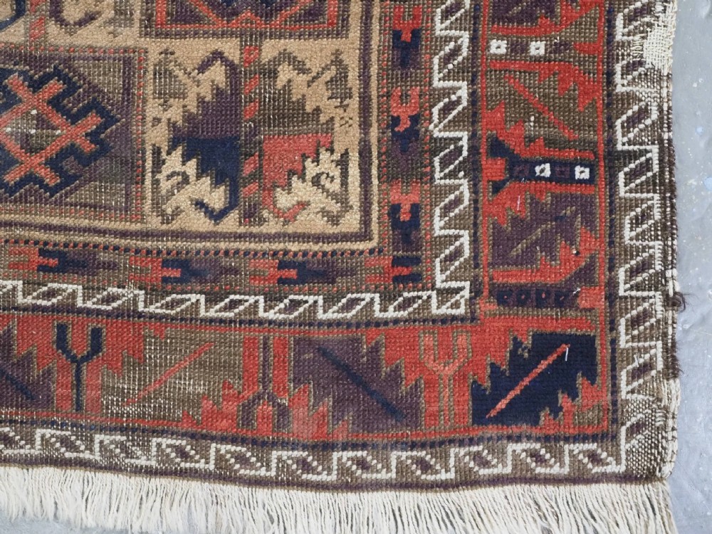 An antique hand-knotted wool prayer rug featuring a central mihrab pattern surrounded by geometric square motifs in dark brown, terracotta, and navy blue tones. View X