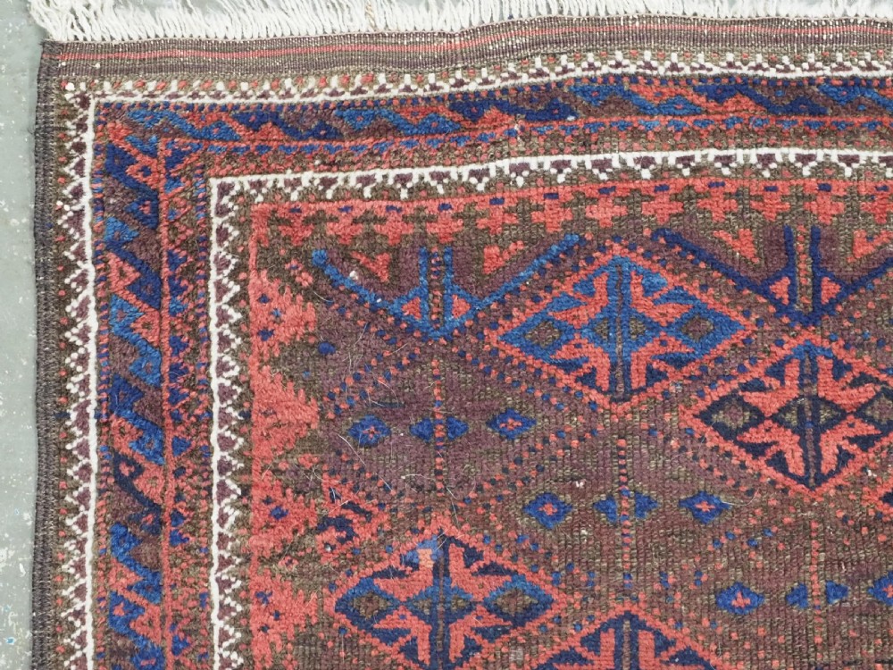 An antique Timuri Baluch hand-knotted wool rug with a dark brown field, repeating indigo and terracotta diamond motifs, and geometric borders. View VI