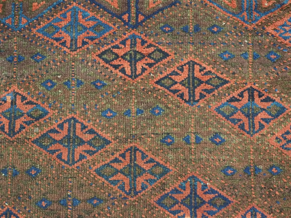 An antique Timuri Baluch hand-knotted wool rug with a dark brown field, repeating indigo and terracotta diamond motifs, and geometric borders. View VIII