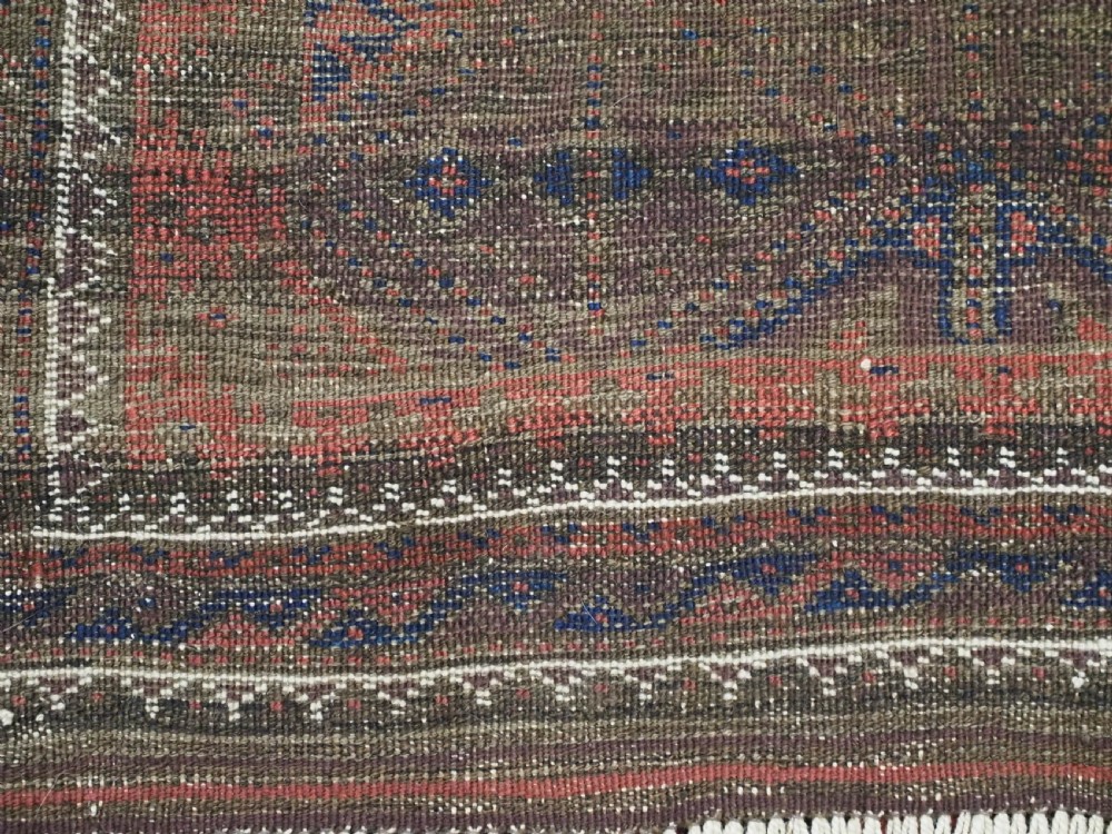 An antique Timuri Baluch hand-knotted wool rug with a dark brown field, repeating indigo and terracotta diamond motifs, and geometric borders. View XII