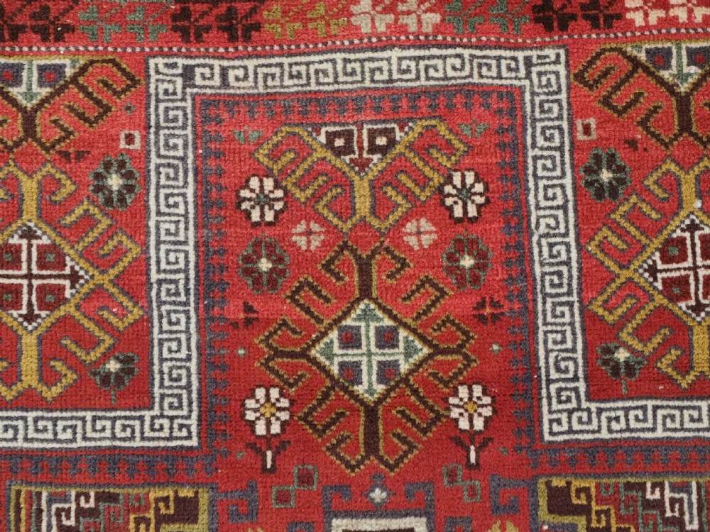 An antique hand-knotted Taimani Baluch prayer rug featuring a deep red field decorated with stepped geometric diamond motifs, a mihrab arch, and stylized geometric borders. View VIII