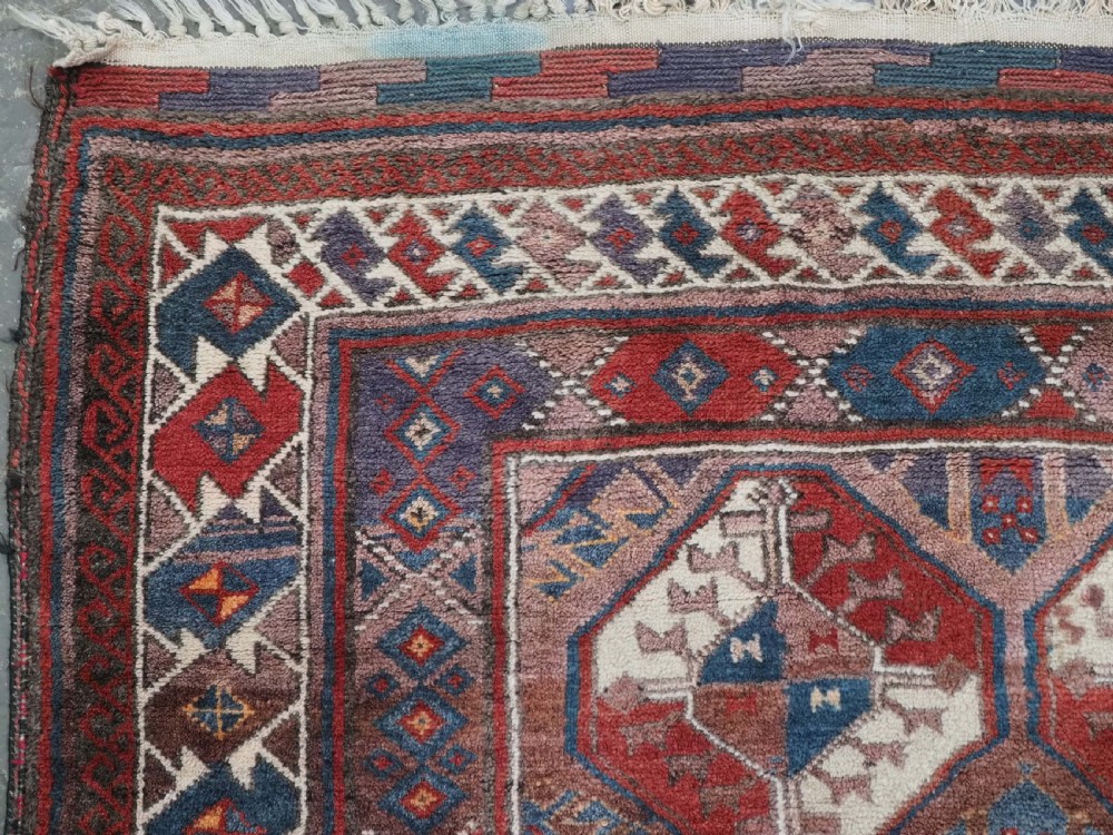 An antique long hand-knotted wool rug featuring geometric octagonal gul motifs in dark brown, red, blue, and cream tones. View VI