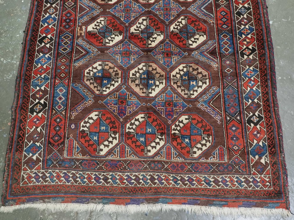 An antique long hand-knotted wool rug featuring geometric octagonal gul motifs in dark brown, red, blue, and cream tones. View VII
