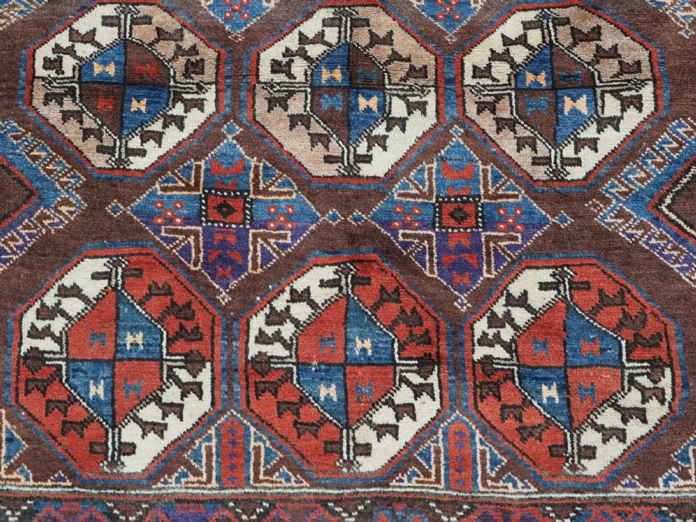 An antique long hand-knotted wool rug featuring geometric octagonal gul motifs in dark brown, red, blue, and cream tones. View XI