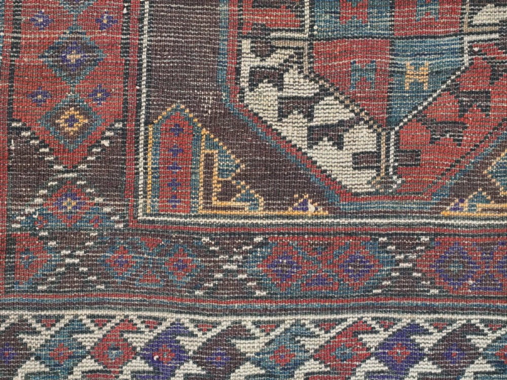 An antique long hand-knotted wool rug featuring geometric octagonal gul motifs in dark brown, red, blue, and cream tones. View XIII