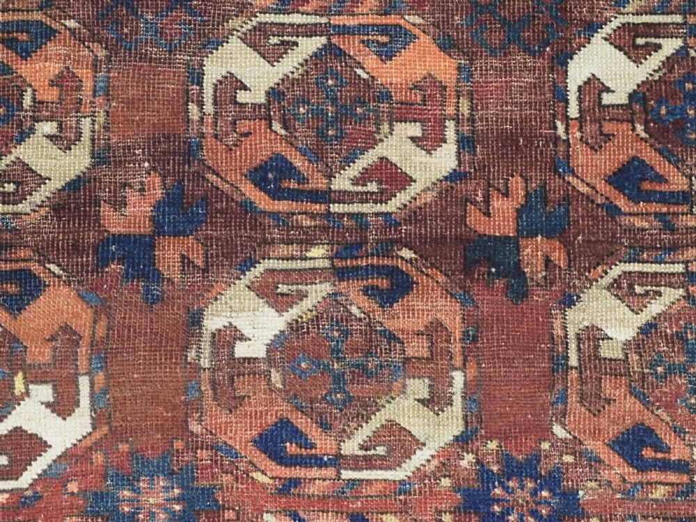 An antique woven wool rug featuring repeated octagonal gol motifs in cream, navy, and terracotta against a rich reddish-brown ground. View VIII