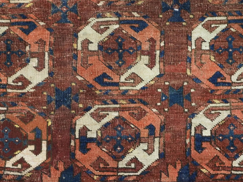 An antique woven wool rug featuring repeated octagonal gol motifs in cream, navy, and terracotta against a rich reddish-brown ground. View IX