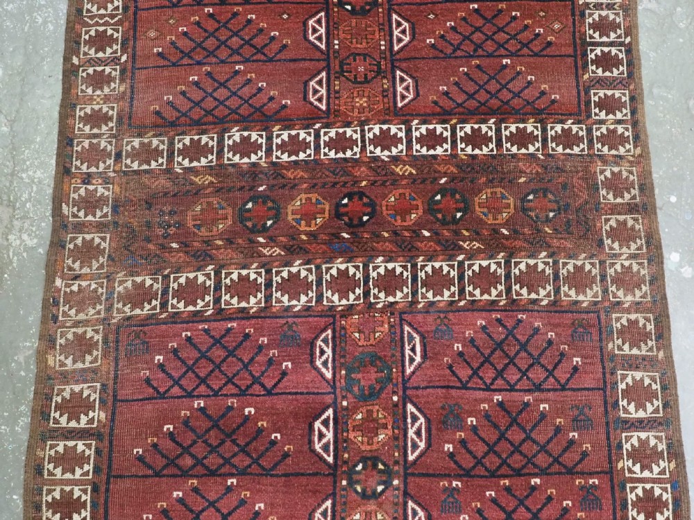 An antique Ersari Turkmen Ensi wool rug featuring a four-panel central field with tree-like motifs surrounded by geometric borders in rich shades of madder red, navy, and cream. View IV