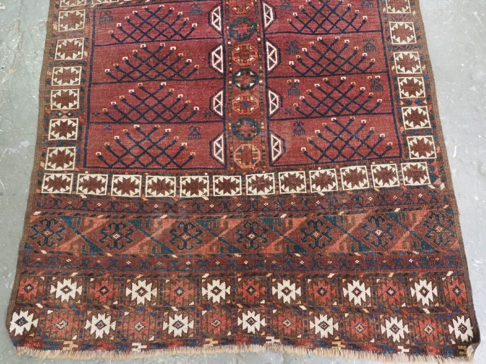 An antique Ersari Turkmen Ensi wool rug featuring a four-panel central field with tree-like motifs surrounded by geometric borders in rich shades of madder red, navy, and cream. View VI
