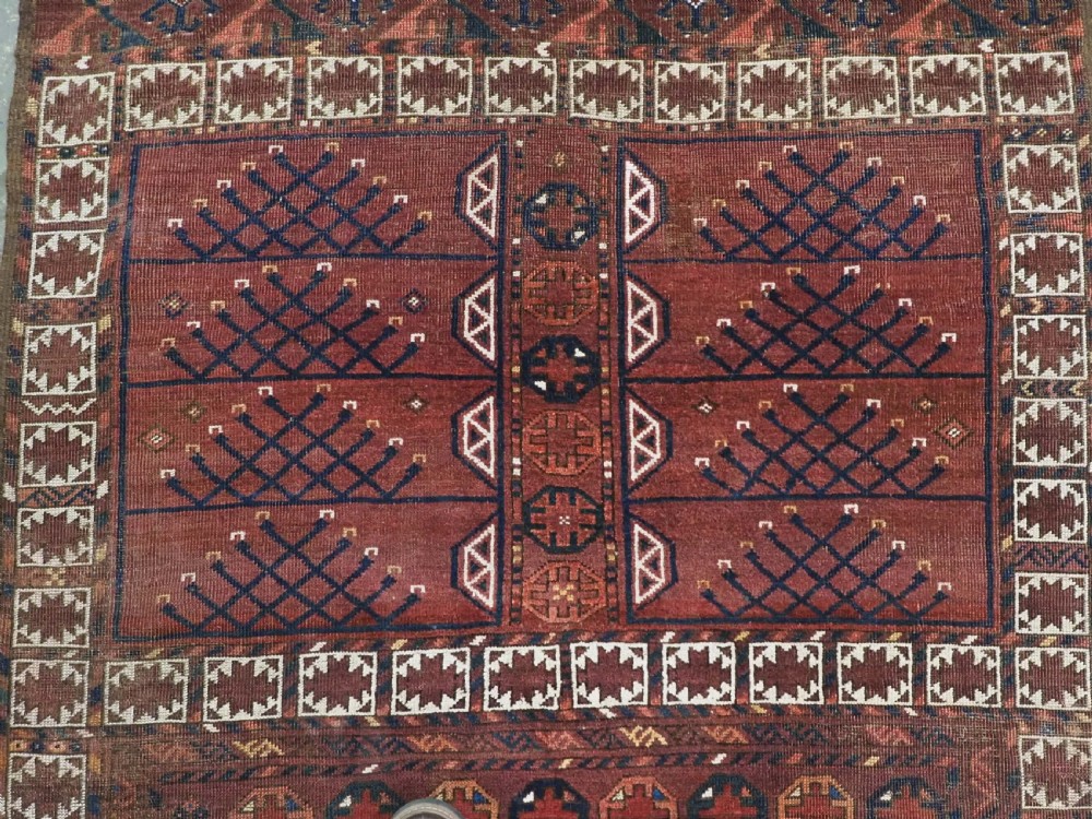 An antique Ersari Turkmen Ensi wool rug featuring a four-panel central field with tree-like motifs surrounded by geometric borders in rich shades of madder red, navy, and cream. View IX