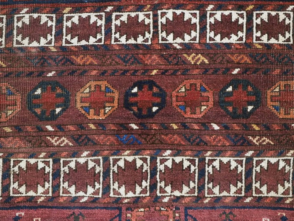 An antique Ersari Turkmen Ensi wool rug featuring a four-panel central field with tree-like motifs surrounded by geometric borders in rich shades of madder red, navy, and cream. View X