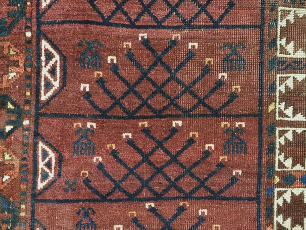 An antique Ersari Turkmen Ensi wool rug featuring a four-panel central field with tree-like motifs surrounded by geometric borders in rich shades of madder red, navy, and cream. View XII