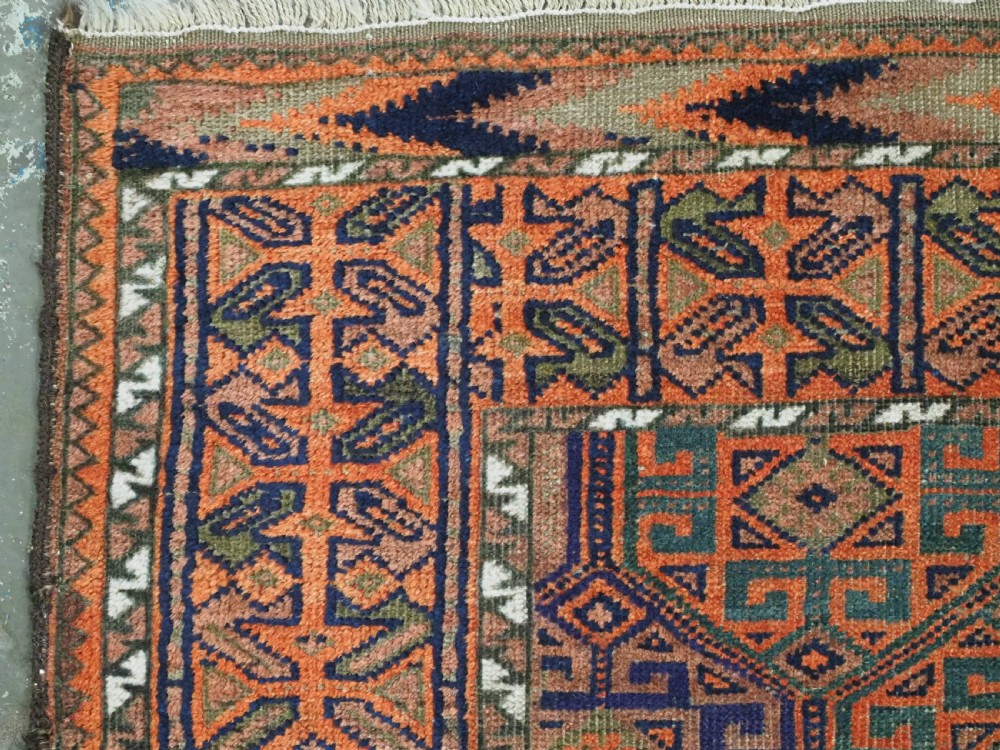 An antique Afghan Baluch wool rug featuring a repeating geometric hexagonal lattice pattern in terracotta orange, navy blue, sky blue, and sage green. View VI
