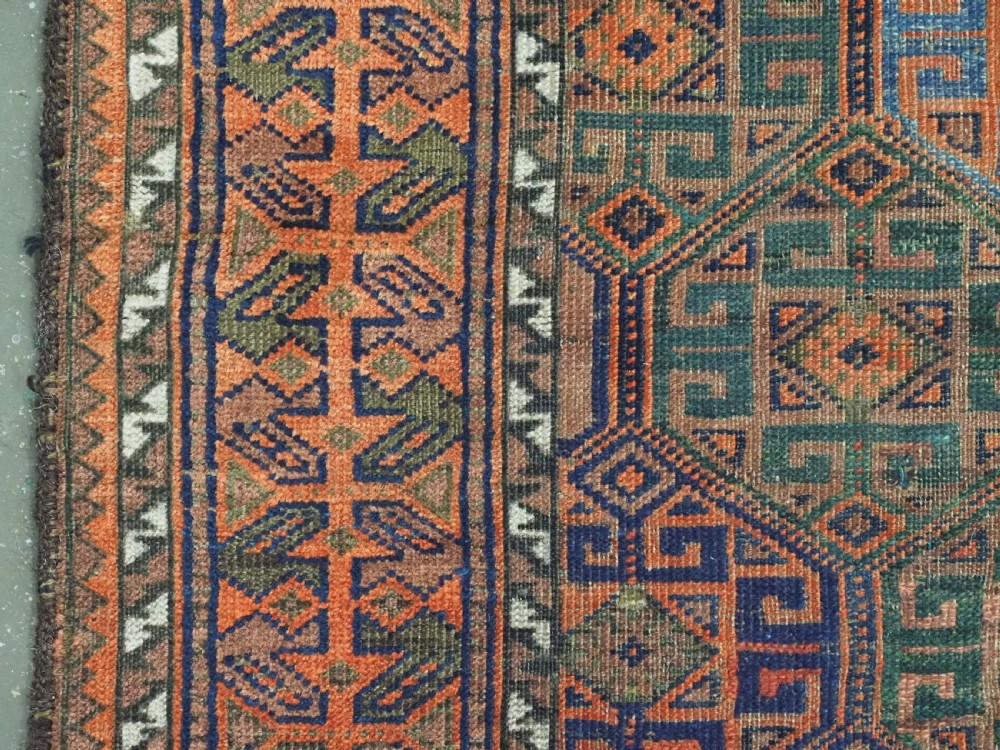 An antique Afghan Baluch wool rug featuring a repeating geometric hexagonal lattice pattern in terracotta orange, navy blue, sky blue, and sage green. View VII