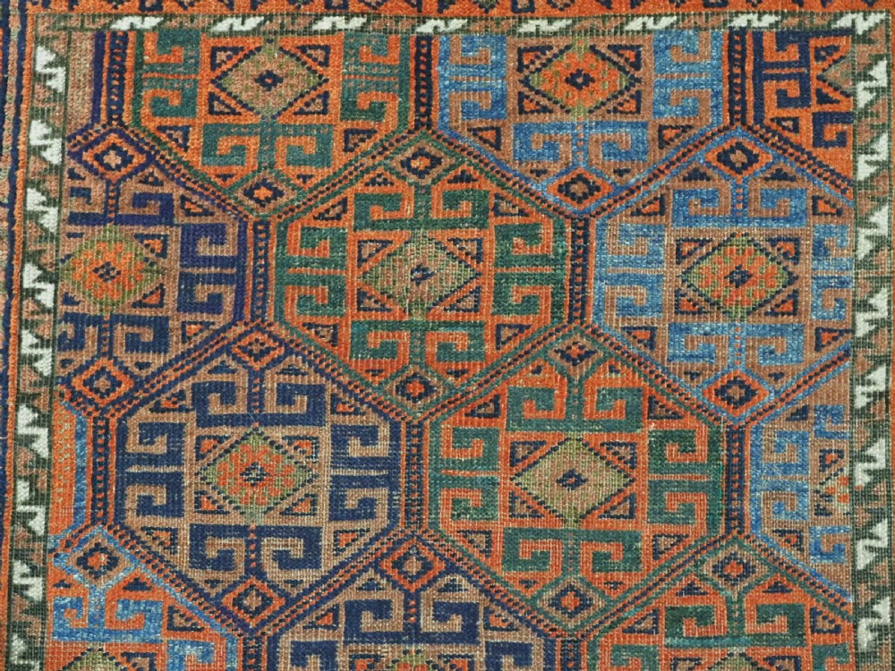 An antique Afghan Baluch wool rug featuring a repeating geometric hexagonal lattice pattern in terracotta orange, navy blue, sky blue, and sage green. View VIII