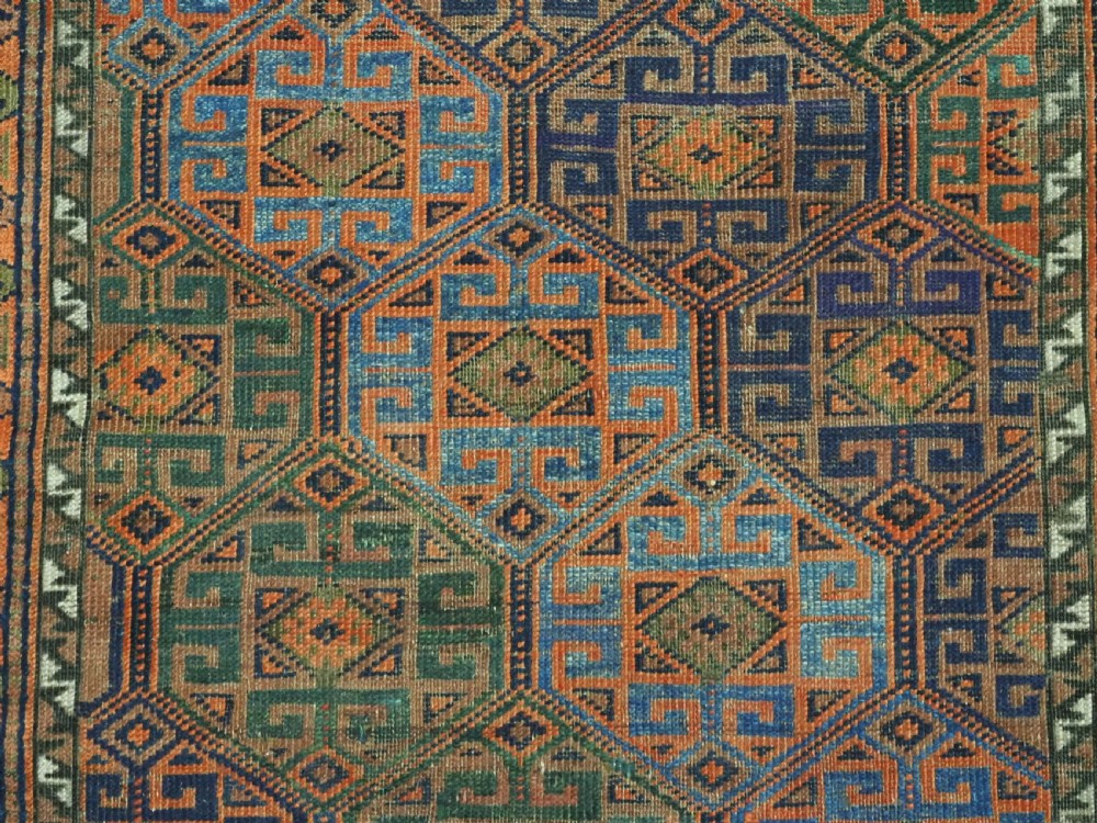 An antique Afghan Baluch wool rug featuring a repeating geometric hexagonal lattice pattern in terracotta orange, navy blue, sky blue, and sage green. View IX