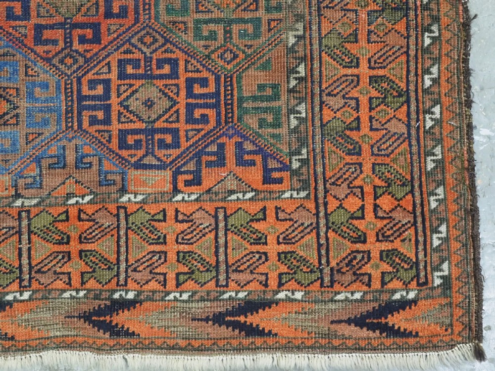 An antique Afghan Baluch wool rug featuring a repeating geometric hexagonal lattice pattern in terracotta orange, navy blue, sky blue, and sage green. View XI