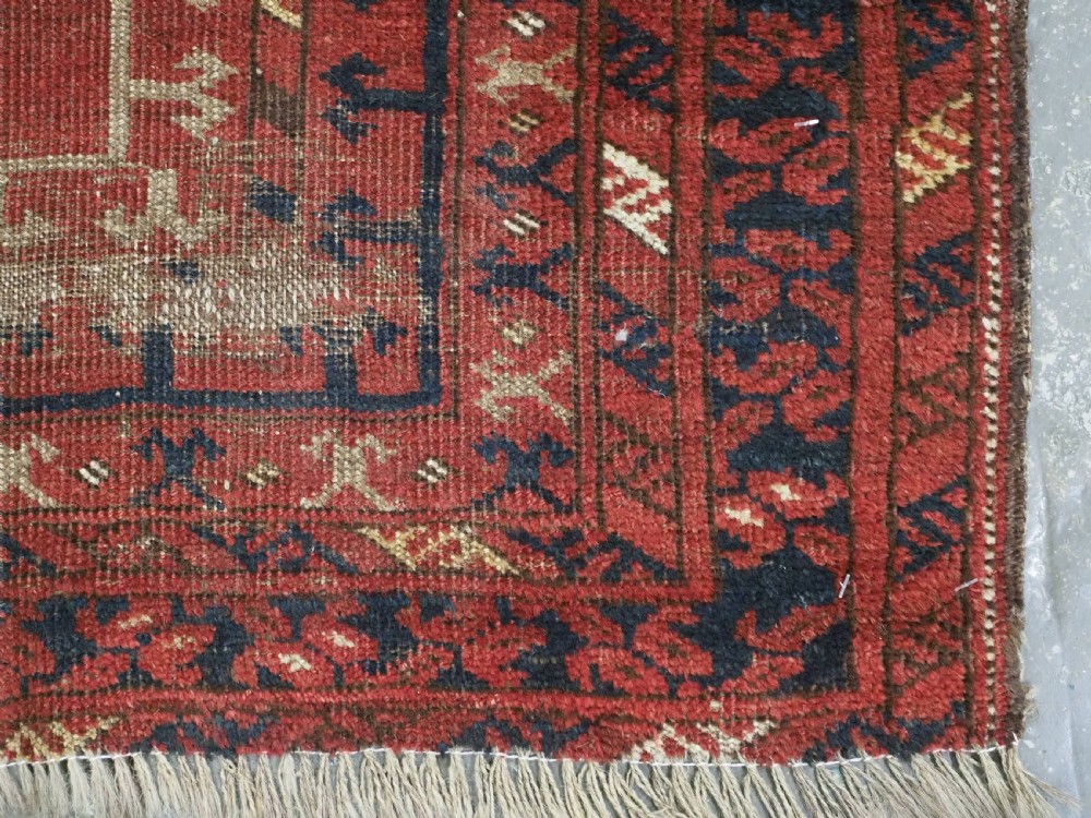 An antique hand-knotted Turkmen prayer rug featuring a red field with a central stepped arch motif and dark blue geometric borders. View XI