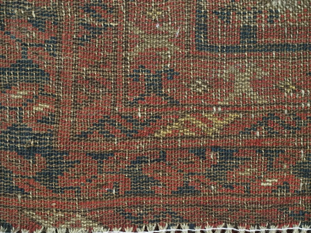 An antique hand-knotted Turkmen prayer rug featuring a red field with a central stepped arch motif and dark blue geometric borders. View XII