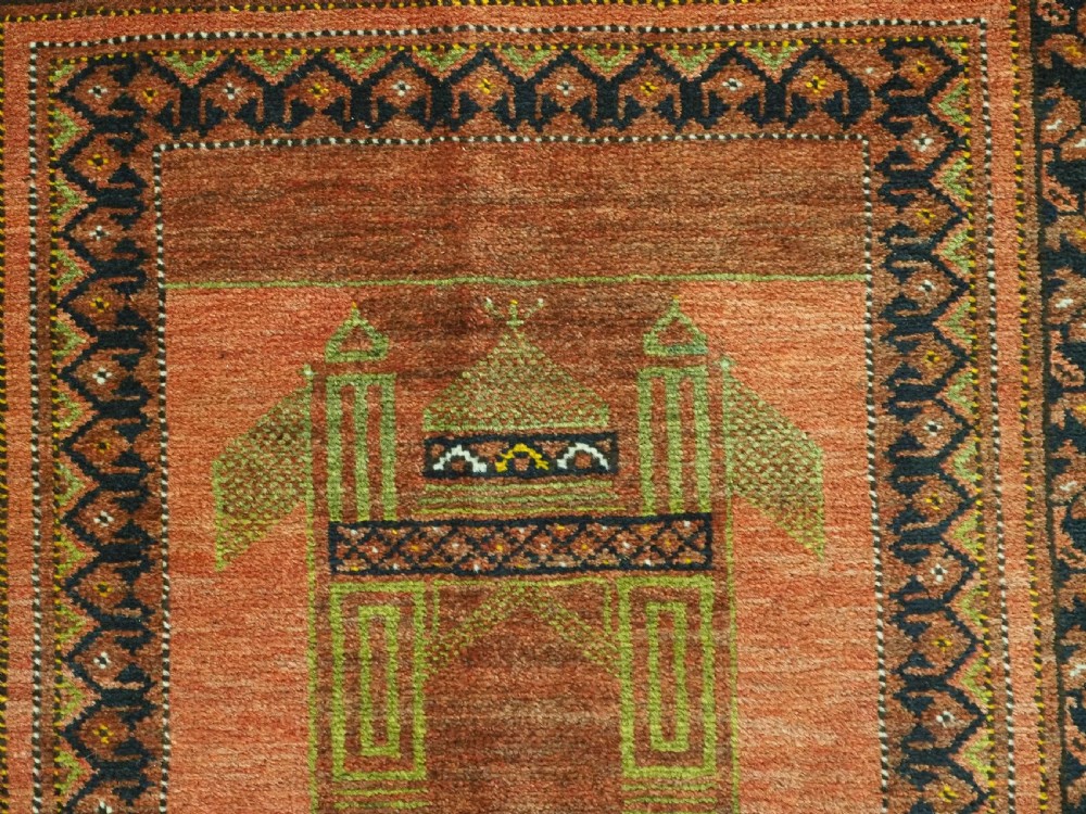 An antique hand-knotted Afghan Turkmen prayer rug featuring a central arch motif on a terracotta wool field framed by dark navy geometric borders. View VI