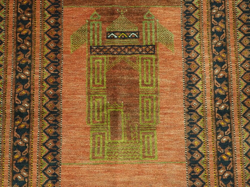 An antique hand-knotted Afghan Turkmen prayer rug featuring a central arch motif on a terracotta wool field framed by dark navy geometric borders. View VIII