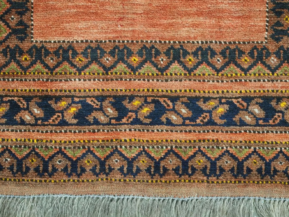 An antique hand-knotted Afghan Turkmen prayer rug featuring a central arch motif on a terracotta wool field framed by dark navy geometric borders. View IX