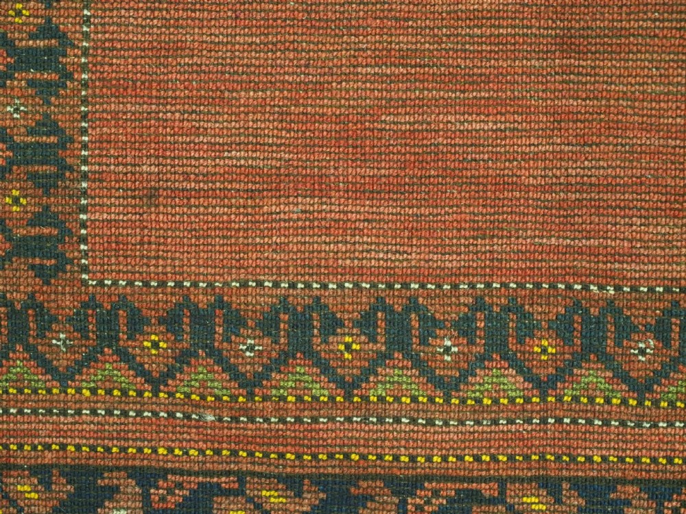 An antique hand-knotted Afghan Turkmen prayer rug featuring a central arch motif on a terracotta wool field framed by dark navy geometric borders. View XI