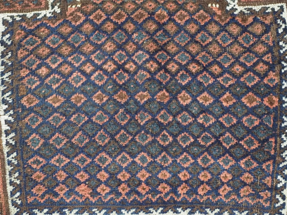 An antique hand-knotted wool Baluch prayer rug featuring a central mihrab niche surrounded by a diamond lattice pattern in dark red, navy blue, and brown tones with light fringe. View VIII