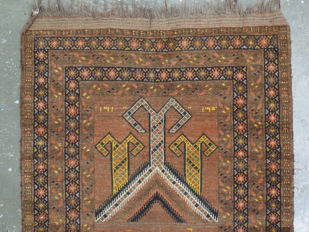 An antique hand-knotted Turkmen wool prayer rug featuring a terracotta-red field with geometric mihrab arches, woven script inscriptions, and patterned borders. View III