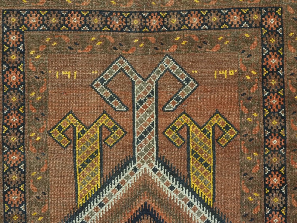 An antique hand-knotted Turkmen wool prayer rug featuring a terracotta-red field with geometric mihrab arches, woven script inscriptions, and patterned borders. View VIII
