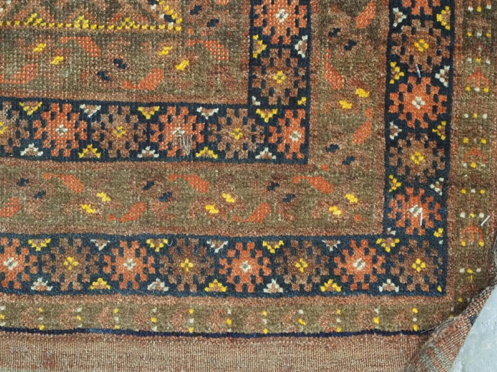 An antique hand-knotted Turkmen wool prayer rug featuring a terracotta-red field with geometric mihrab arches, woven script inscriptions, and patterned borders. View XVII